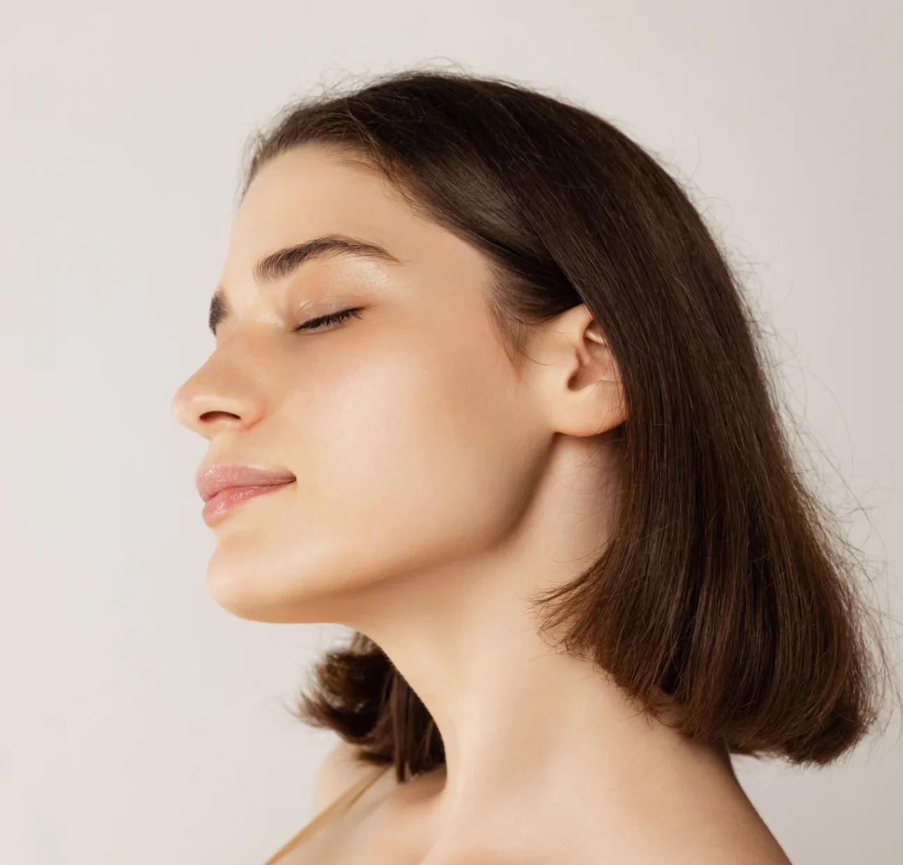 Close up portrait of young beautiful woman posing isolated over grey studio background. Sharp cheekbones. buccal fat reduction featured image