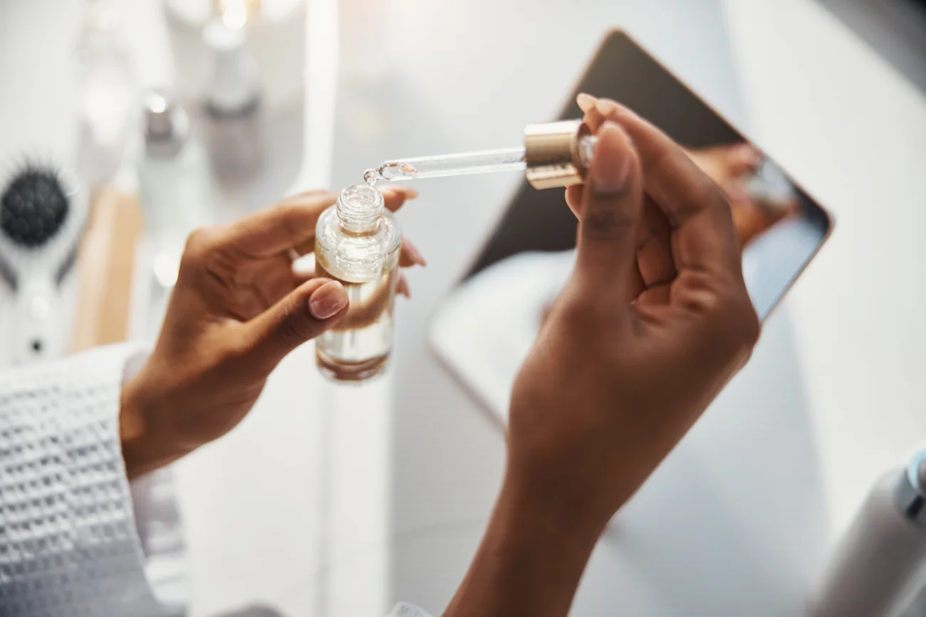 Female hands holding bottle of vitamin serum and pipette