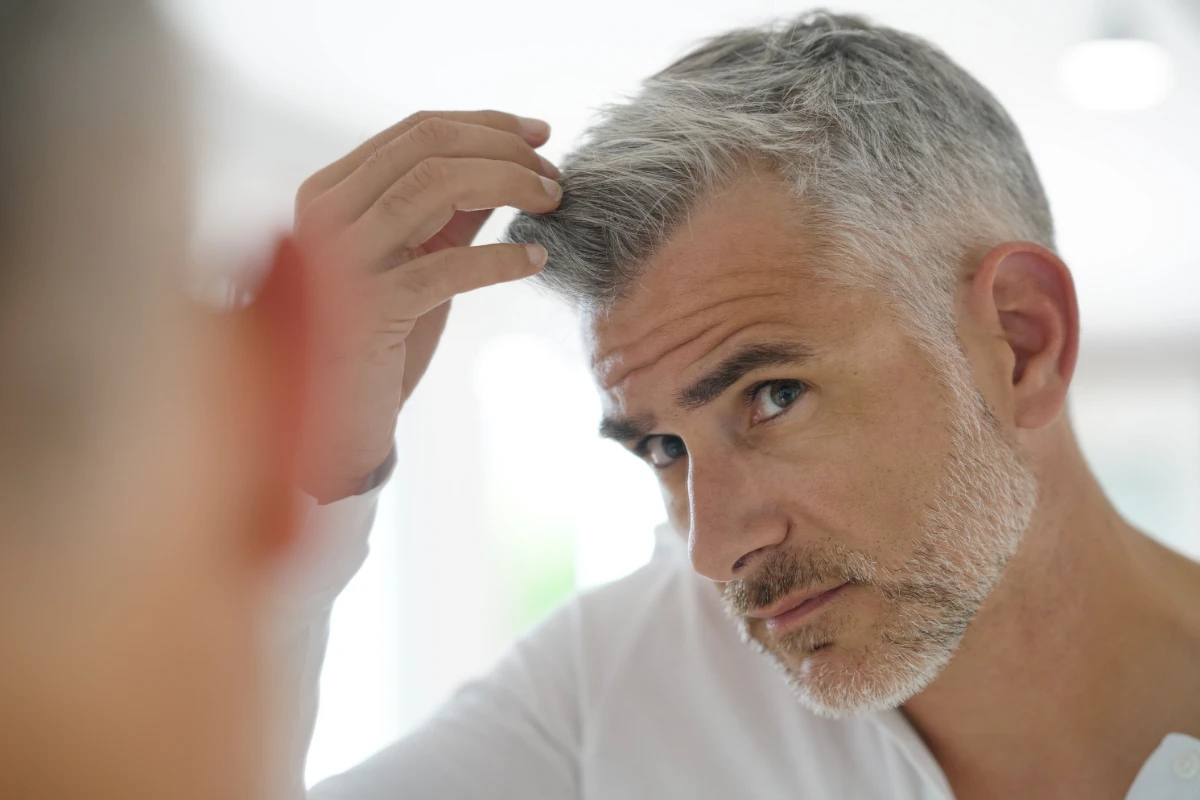 Middle aged man inspecting hair for hair loss