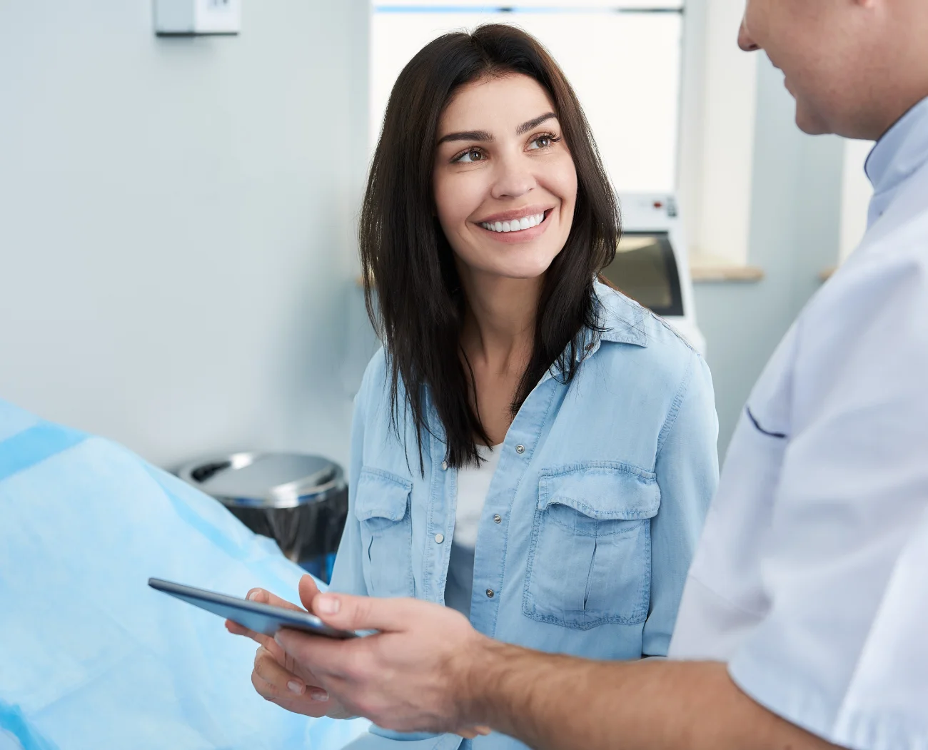 Plastic surgeon giving tablet to female patient to filling out questionnaire in clinic of beauty