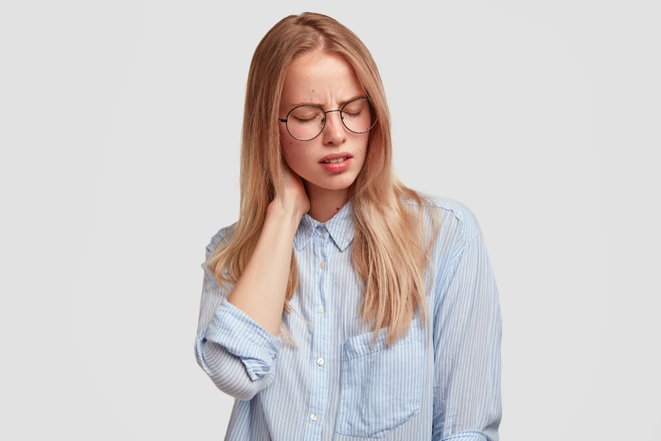 Tired female office worker in spectacles has pain in neck. facial trauma treatment