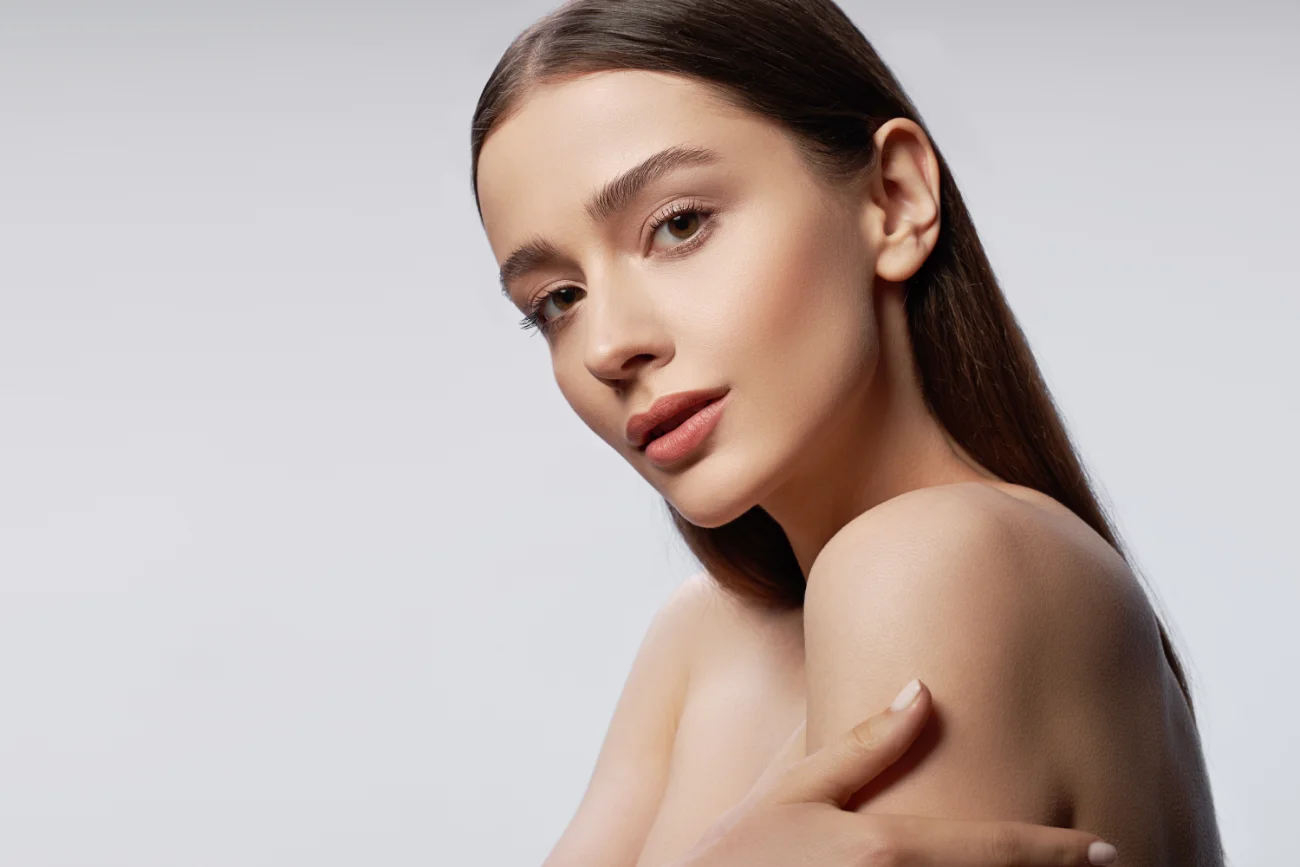 Young pretty lady with natural makeup posing against light gray background