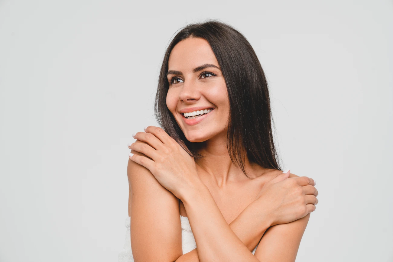 Young caucasian pretty woman lady girl in spa bath towel hugging embracing herself isolated in grey background