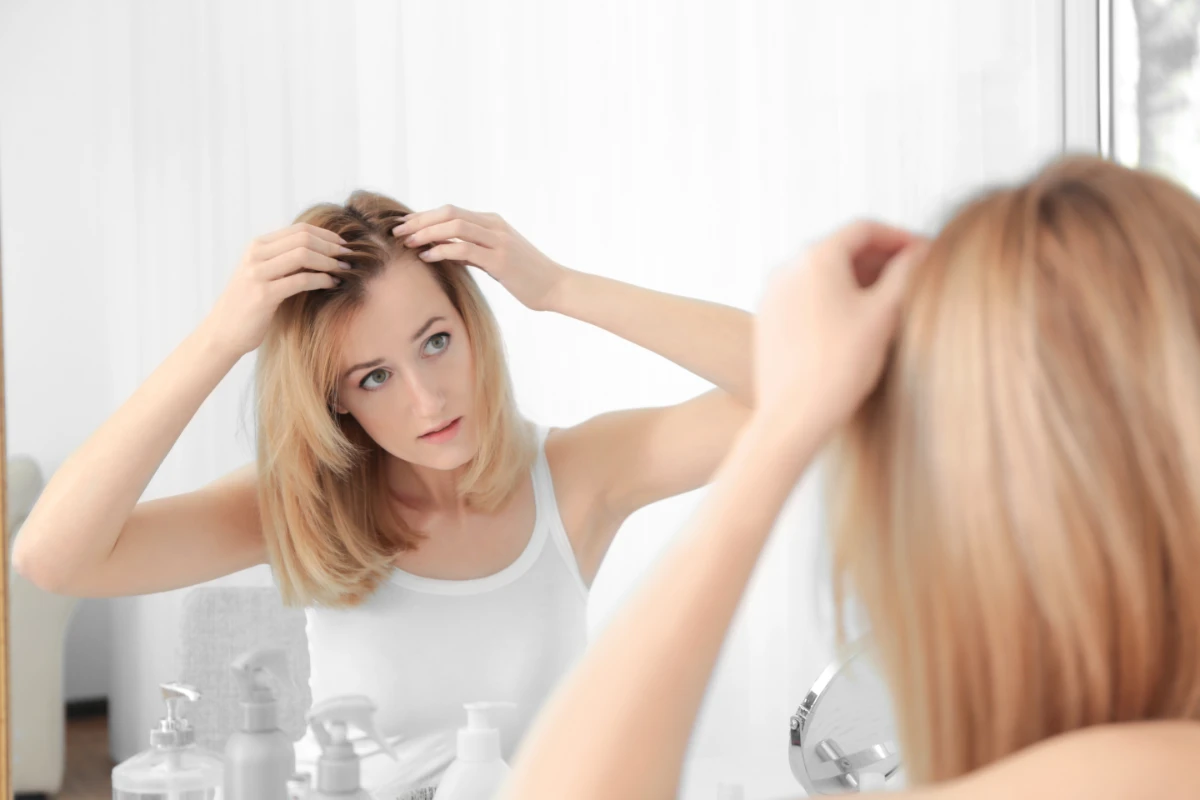 Young woman inspecting hair for hair loss