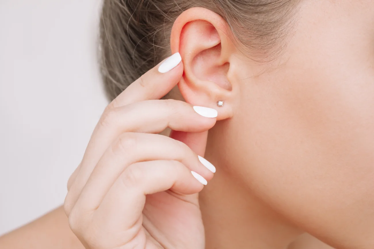 otoplasty ear featured image. Cropped shot of a young woman wearing elegant stud earrings on a gray background
